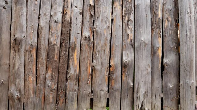 Closeup dolly shot of camera moving along long wooden fence made of round logs. Perfect rustic or countryside backdrop