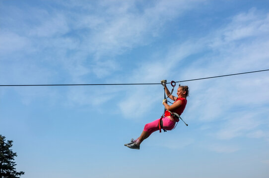 Side View Of Woman Ziplining Against Sky