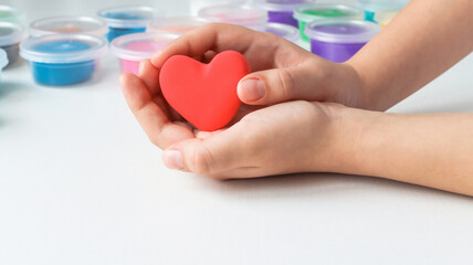 Children's hands hold a red heart made by a child. Copy space. the concept of love, support, and help.