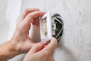 A worker removes the light switch for wallpapering.