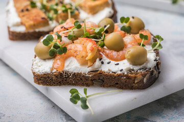 Prawns toast with a micro-green, olives on  wooden background,  concept of healthy eating,  assortment of bruschetta