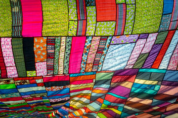 A huge colorful artistic fabric, made from a combination of colorful pieces of unused and collected clothes by a tailor.