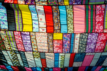 A huge colorful artistic fabric, made from a combination of colorful pieces of unused and collected clothes by a tailor.