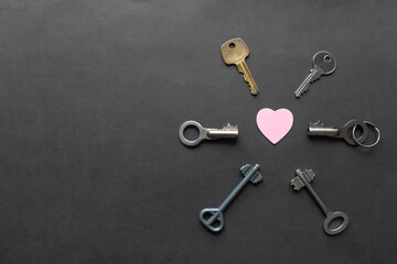 Key to heart concept. Way to heart. Heart and many keys around on dark black background with copy space