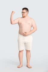 Overweight man on grey background. Weight loss concept