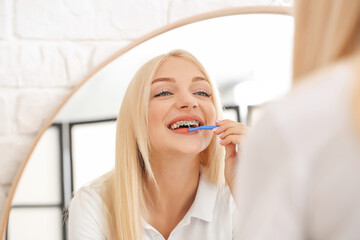 Young woman with dental braces and toothbrush at home