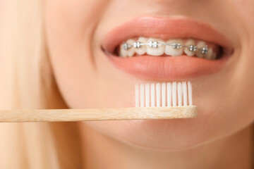 Young woman with dental braces and wooden toothbrush, closeup