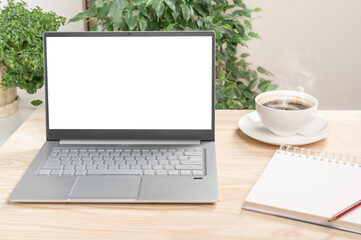 Fototapeta premium mockup laptop on wooden table, Front view of the laptop is on work table with notebook and cup of coffee. Laptop or notebook with blank screen on wood table