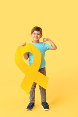 Little boy with golden ribbon on color background. Childhood cancer awareness concept