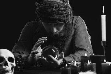 Black and white photo of male fortune teller at table