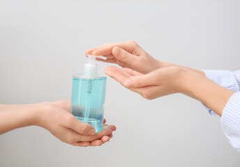 People with sanitizer on grey background