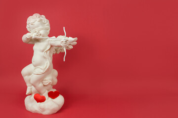 Statuette of an angel with a bow and arrow. Angel-cupid with a bow and arrow. The concept of Valentine's Day. Arrow of love. Cupid shoots a love arrow from a bow on Valentine's Day.