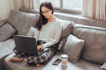 Young woman working on laptop and sitting at home. Beautiful busineeswoman working at home and smiling. Working at home during Coronavirus or Covid-19 quarantine.