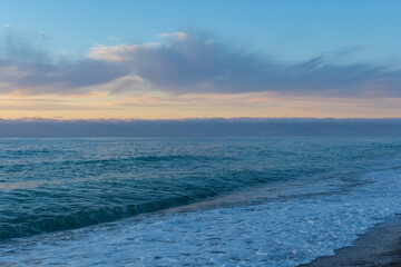Obraz premium Blue evening serene sea. Calm seascape in azure and pearl shades. Natural background in the twilight. The concept of relaxation and relaxation. Beach with small pebbles, small waves with foam