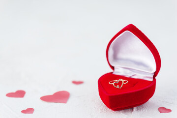 Ring in the form of a heart in a box on a background of red hearts. Valentine's Day.