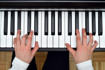 Young girl playing the piano. Child practicing on the modern electric piano at home. Music lesson. Close-up. High angle view.