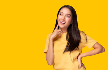 Portrait young asian woman look at copy space Beautiful girl wear yellow T shirt with yellow background at studio Pretty asia female get confident. Female get satisfied something Lovely lady get happy