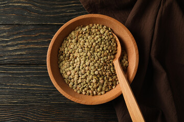 Kitchen towel, bowl with legumes and spoon on wooden background
