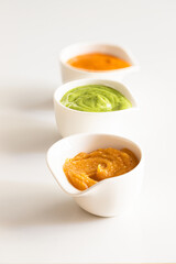 Three famous Canary islands sauces Mojo picon , Red hot sauce, and  Mojo verde , Green sauce and Almogrote, cheese  sauce  in bowl on white background