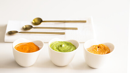 Three typical Canary Islands sauces, mojo picon, mojo verde  and almogrote  in ceramic bowl on modern restaurant table - obrazy, fototapety, plakaty