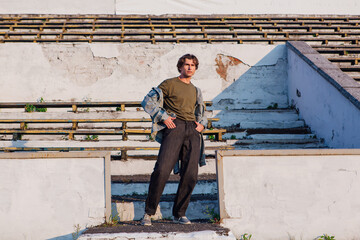 Tall handsome man on the crushed tribune of the old stadium