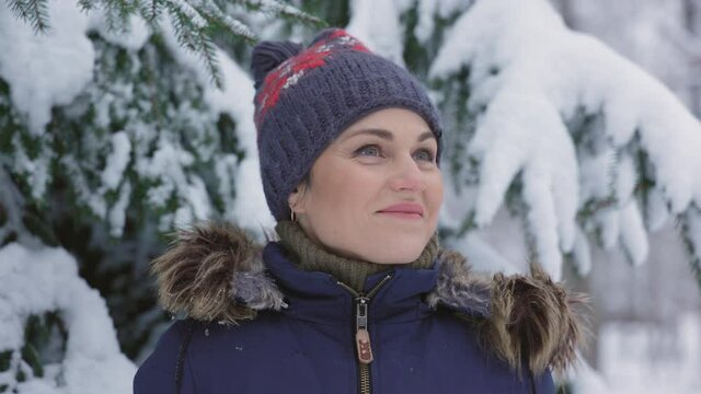 Video portrait of woman near spruce in winter forest