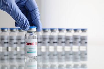 Doctor taking vaccine for immunization against COVID-19 from table