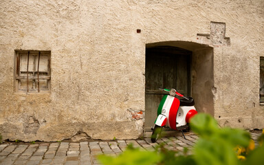 Vintage motorbike in italian flag colors parked near old rustic wall. Inspiring atmospheric spirit...