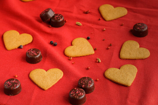 Valentine's day cookies with heart shape isolated on red with some chocolates on the background. Valentine's day concept. Selective focus