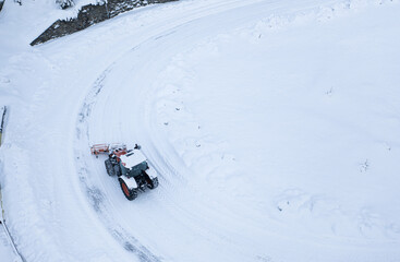 Snow plough truck cleaning a road through the mountains after winter massive snowfall aerial view