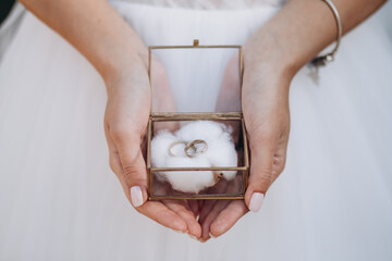 wedding rings in the hands of the bride and groom. Gold rings in a decorative glass box with cotton - 404753506