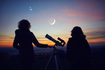 Mother and daughter observing stars, planets, Moon and night sky with astronomical telescope.