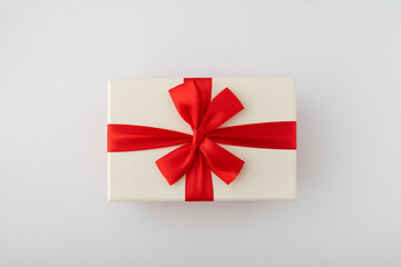 White gift box with red ribbon and bow on white background. Top view.