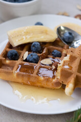 Breakfast with Belgian waffles with honey, blueberries, banana and almonds  on a linen tablecloth. 