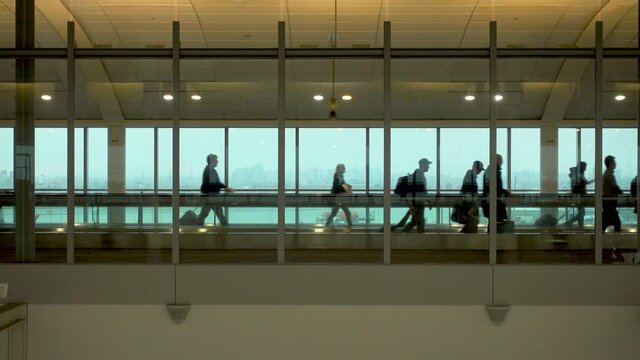 Silhouette of some people walking on the moving walkway, embarking from the airport of New York during the Covid-19 pandemic.