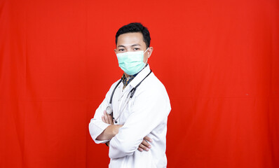 smiling young male doctor wear mask with stethoscope over neck in medical coat isolated red background