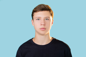 Confident teenager portrait. Youth lifestyle. Motivation inspiration. Relaxed guy in black t-shirt looking at camera isolated on blue copy space background. - obrazy, fototapety, plakaty