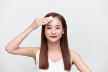 Fototapeta premium Face skin care. Smiling woman using facial oil blotting paper portrait