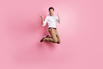 Fototapeta na wymiar Full size photo of optimistic guy jump show rock sign wear white shirt trousers sneakers isolated on pink color background