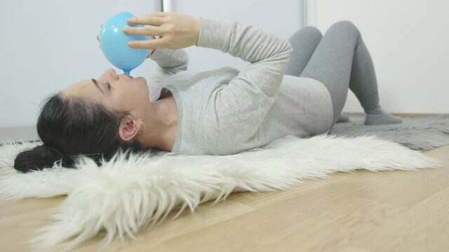 Woman lying on floor and blowing balloon