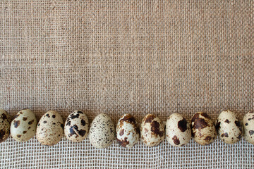 Close up of organic farmer quail eggs on natural burlap, linen or hemp fabric background. Easter and organic food concept with copy space for creative design. Top view