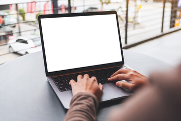 Mockup image of a woman using and typing on laptop computer with blank white desktop screen on the table