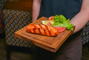 Salmon steak with vegetables cooked on the grill served in a restaurant or diner. Waiter service, eating out concept.