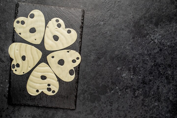 heart shaped cheese slices on stone background with copy space