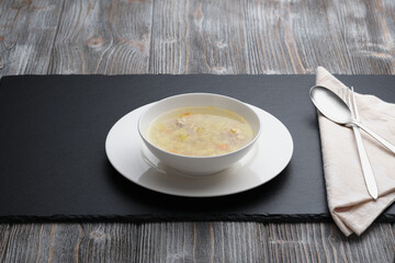 White plate with chicken soup on wood table