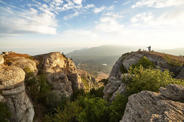 steep cliff in the rocks against the background of mountains and cloudy blue sky