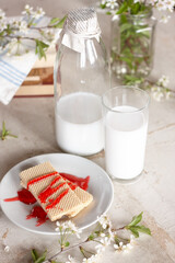 jar and glass with milk and sweet waffles covered with red syrup on a vintage steel background