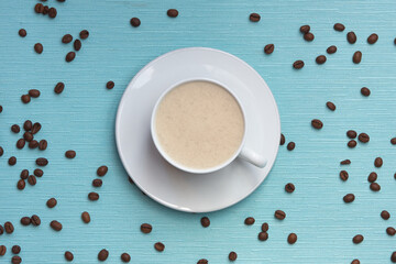 a cup of coffee on a blue textured background with scattered grains