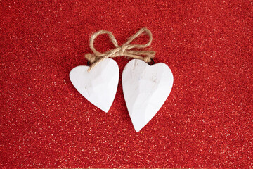 Decorative white wooden hearts on red shiny background