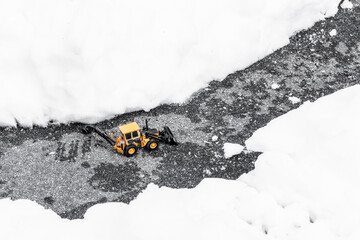 Model of digger circulating on a clear road among large amounts of snow. Problems with unfavorable...